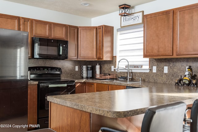 kitchen with tasteful backsplash, brown cabinetry, a sink, black appliances, and a kitchen bar