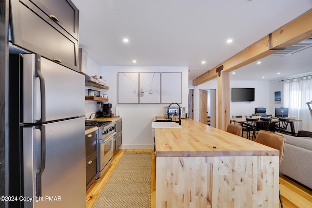 kitchen with stainless steel appliances, light wood-type flooring, open floor plan, and a sink