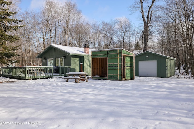 view of front of home with a garage, an outdoor structure, a chimney, and a wooden deck