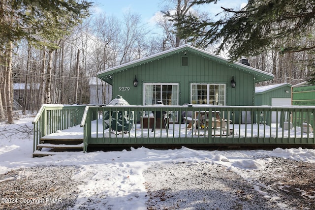 snow covered rear of property with a deck