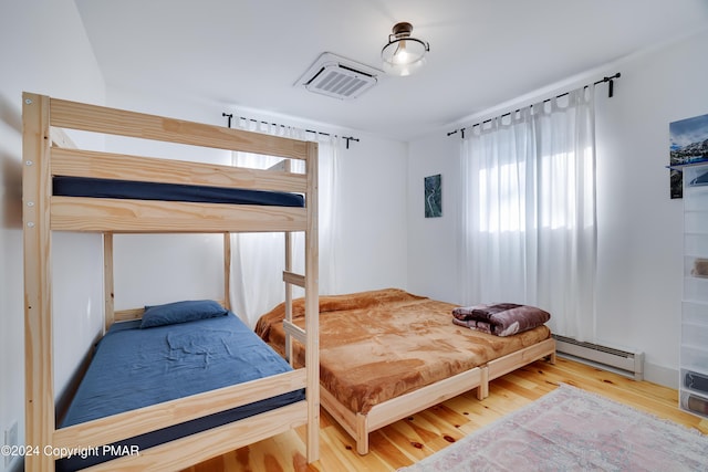 bedroom featuring visible vents, baseboard heating, and wood finished floors