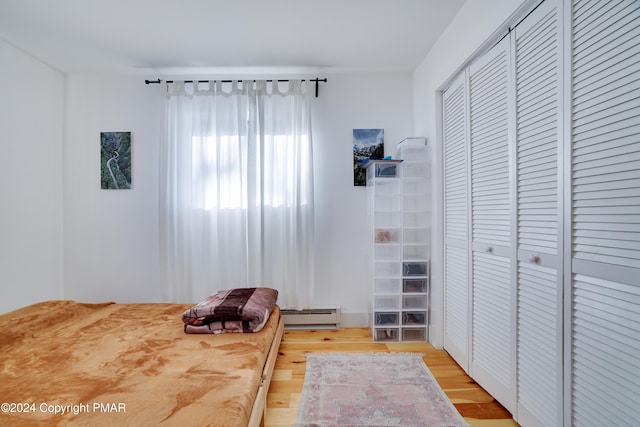 bedroom featuring light wood-style floors, a closet, and baseboard heating