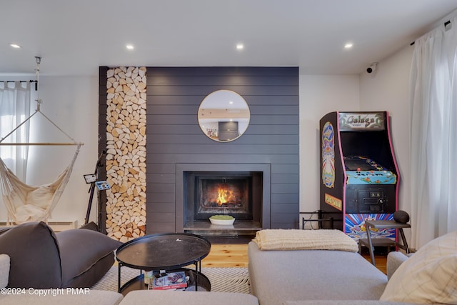 living area featuring recessed lighting, a large fireplace, and wood finished floors