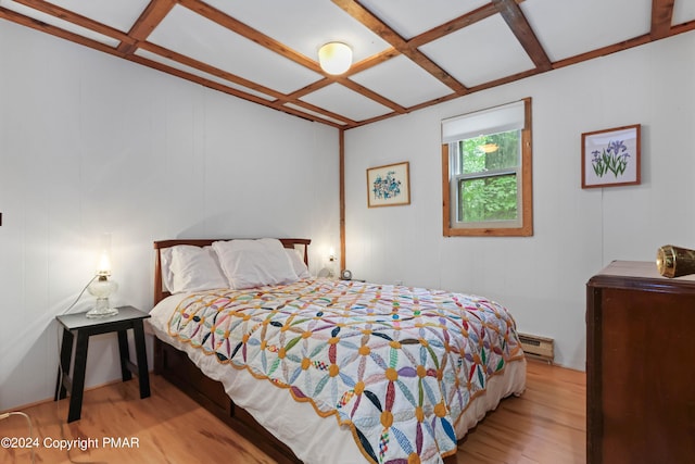 bedroom with a baseboard radiator, coffered ceiling, beamed ceiling, and wood finished floors