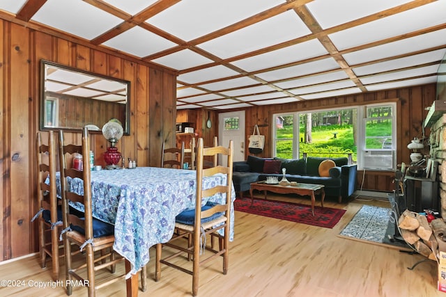 dining space featuring a baseboard heating unit, coffered ceiling, wooden walls, and wood finished floors