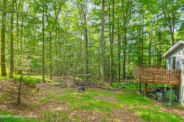 view of yard featuring a deck and a view of trees