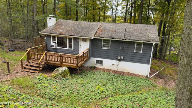 view of front of property with a deck, cooling unit, a shingled roof, and a chimney