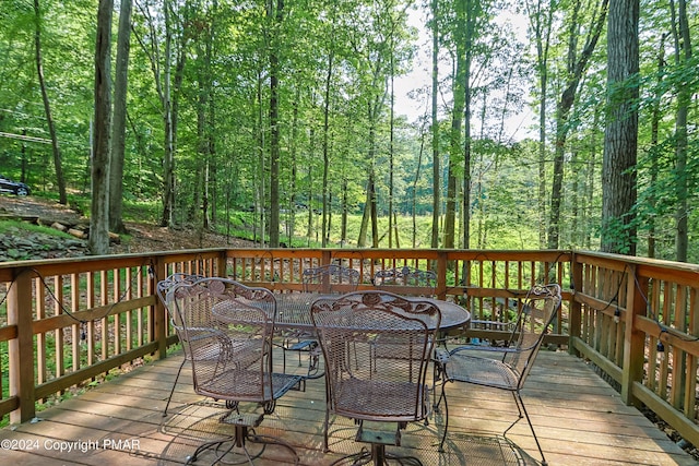 deck featuring a wooded view and outdoor dining space