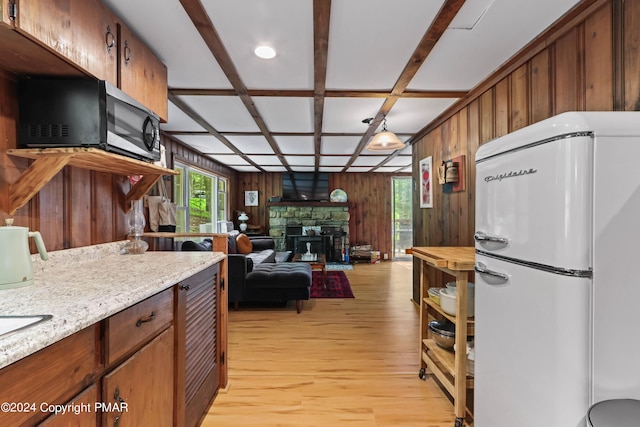 kitchen featuring stainless steel microwave, freestanding refrigerator, wooden walls, light wood-type flooring, and coffered ceiling