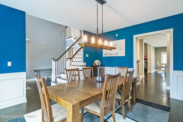 dining area featuring a wainscoted wall, stairway, a decorative wall, and a notable chandelier