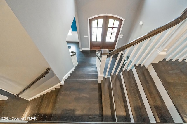 staircase featuring arched walkways, french doors, wood finished floors, and baseboards