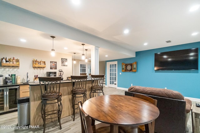 bar with pendant lighting, recessed lighting, light wood-style floors, wet bar, and beverage cooler