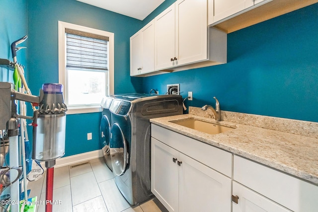 clothes washing area with light tile patterned floors, a sink, visible vents, cabinet space, and washer and clothes dryer