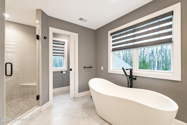 bathroom featuring marble finish floor, a soaking tub, visible vents, a stall shower, and baseboards