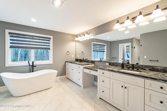 full bath featuring a sink, visible vents, baseboards, a freestanding bath, and marble finish floor