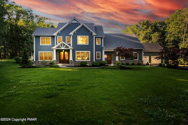 view of front of house with a garage, stone siding, and a lawn