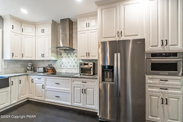 kitchen featuring stone counters, stainless steel appliances, white cabinets, decorative backsplash, and wall chimney exhaust hood