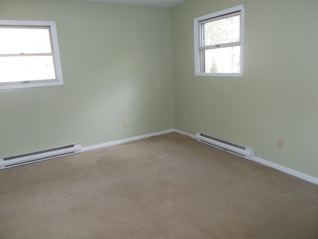 empty room featuring plenty of natural light, carpet floors, and a baseboard radiator