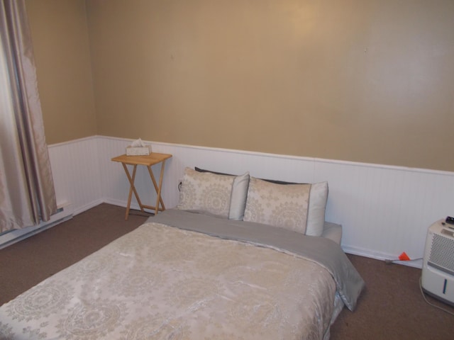 carpeted bedroom featuring a wainscoted wall and a baseboard radiator