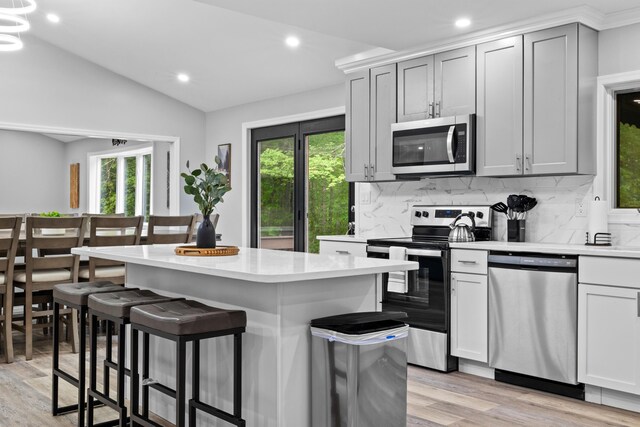 181 Williams Ln, Scotrun, PA 18355 - kitchen featuring appliances with stainless steel finishes, vaulted ceiling, light wood finished floors, a kitchen breakfast bar, and light countertops
