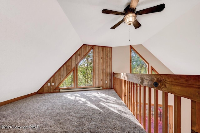 additional living space featuring vaulted ceiling, baseboard heating, carpet flooring, and wooden walls