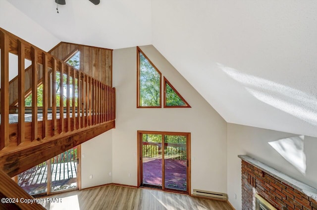 unfurnished living room featuring high vaulted ceiling, wood finished floors, a ceiling fan, baseboards, and baseboard heating