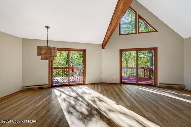 unfurnished living room with plenty of natural light, a baseboard heating unit, and wood finished floors