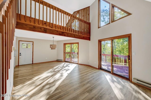 unfurnished living room with baseboards, a baseboard radiator, a baseboard heating unit, and wood finished floors