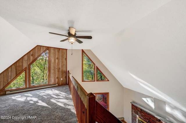 bonus room with ceiling fan, lofted ceiling, a baseboard radiator, wood walls, and carpet