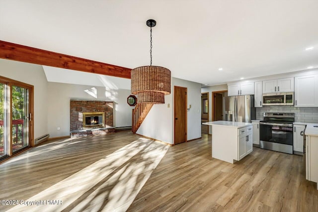kitchen with a center island, stainless steel appliances, light countertops, backsplash, and open floor plan