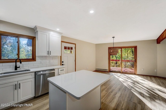 kitchen featuring light countertops, a sink, backsplash, and stainless steel dishwasher