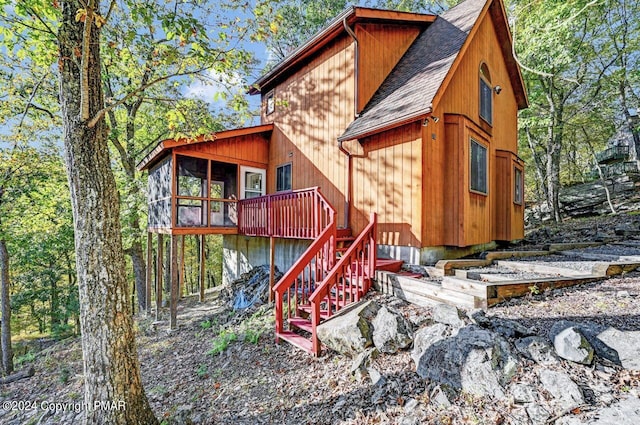 rear view of property with a shingled roof, stairway, and a wooden deck