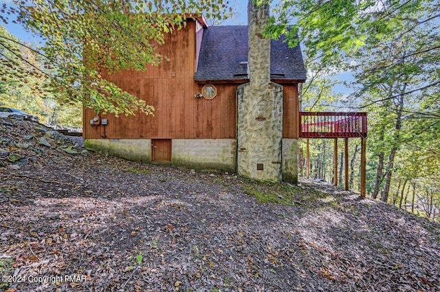 view of side of property with crawl space, a chimney, and roof with shingles
