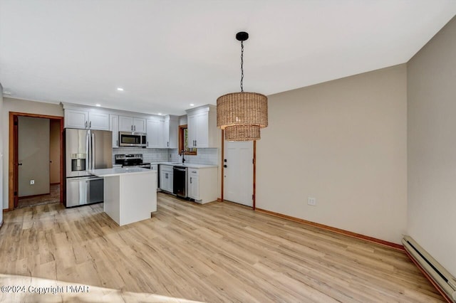 kitchen with a baseboard heating unit, stainless steel appliances, light countertops, backsplash, and light wood finished floors
