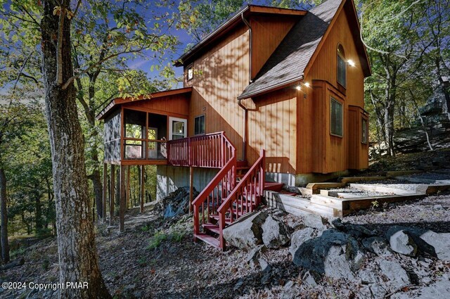back of property featuring a shingled roof, stairway, and a wooden deck