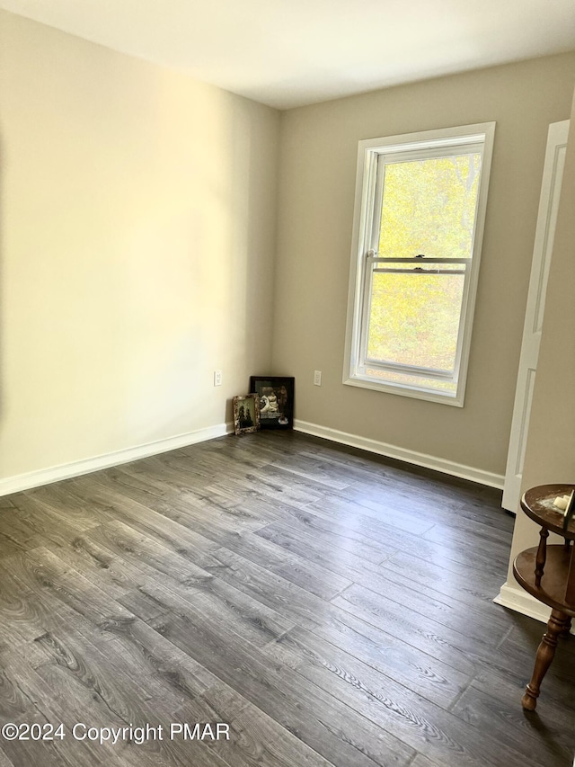 unfurnished room featuring dark wood-type flooring and baseboards