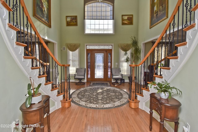 foyer entrance with stairs, a towering ceiling, and hardwood / wood-style floors