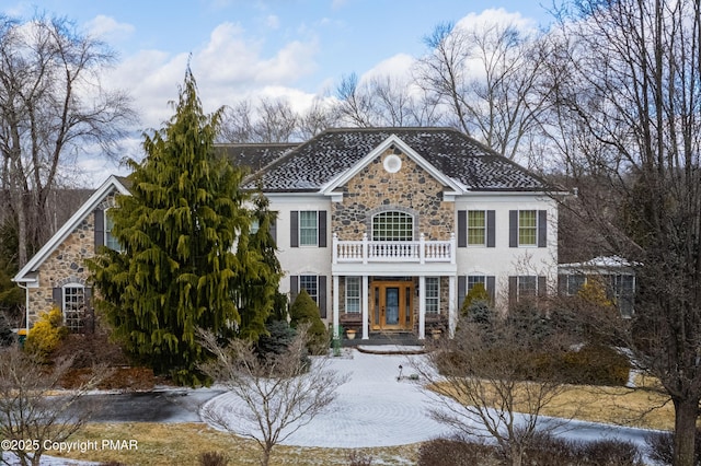 view of front of property featuring french doors, stone siding, a balcony, and stucco siding