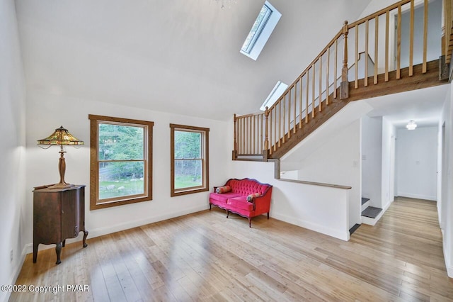 sitting room with stairway, wood finished floors, baseboards, and a skylight