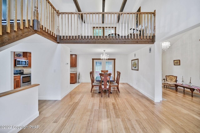 dining space featuring light wood finished floors, a high ceiling, an inviting chandelier, and baseboards