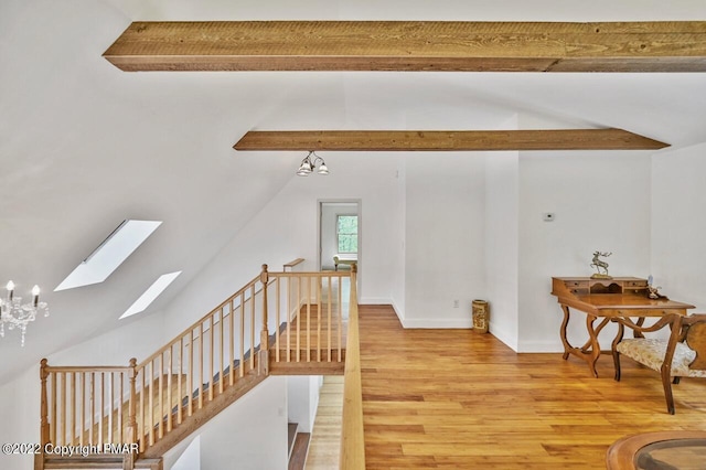 bonus room featuring a chandelier, baseboards, light wood-style floors, and vaulted ceiling with skylight