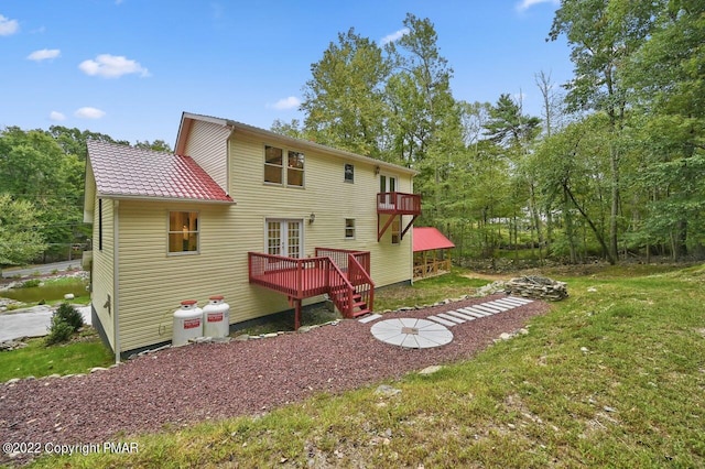 rear view of house featuring a wooden deck and a yard