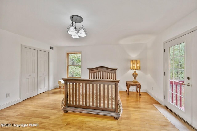 bedroom featuring access to outside, light wood-style floors, a closet, baseboards, and visible vents
