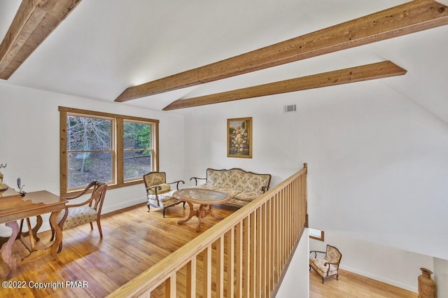 interior space featuring beam ceiling, visible vents, light wood-type flooring, and baseboards