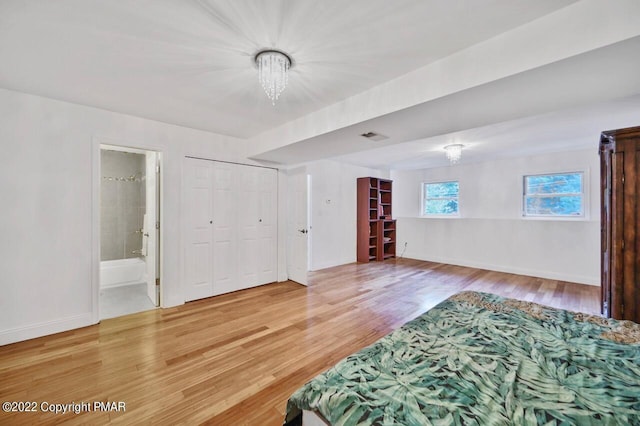 bedroom with a chandelier, light wood-type flooring, ensuite bath, and baseboards