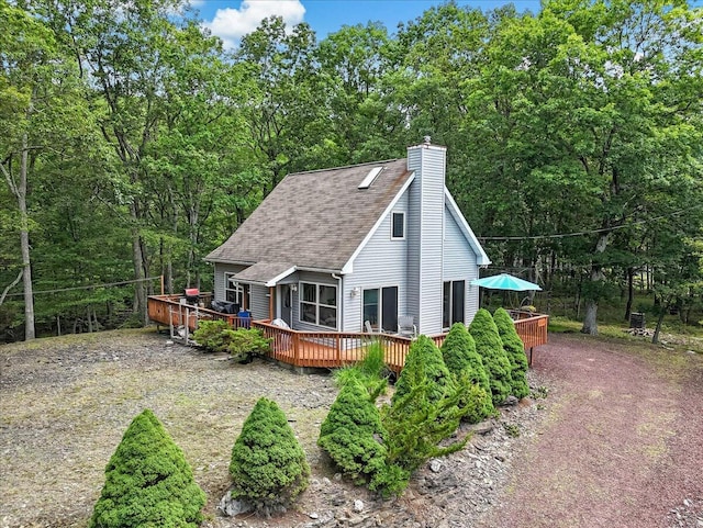 2218 Lancaster Dr, Lehman, PA 18324 - rear view of house featuring a wooden deck, roof with shingles, a chimney, and a wooded view