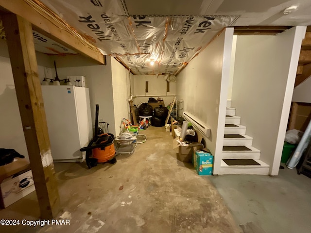 unfinished basement featuring stairs and freestanding refrigerator