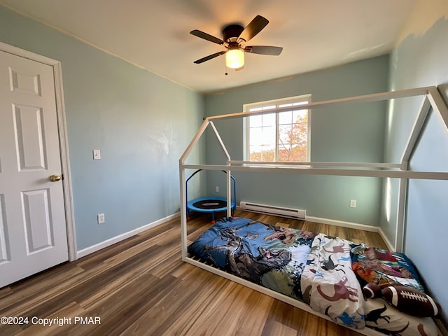 bedroom featuring a baseboard heating unit, a ceiling fan, baseboards, and wood finished floors