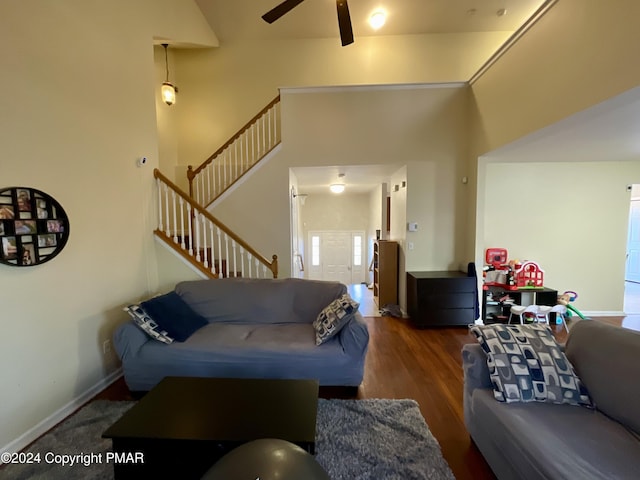 living area featuring wood finished floors, a towering ceiling, baseboards, and stairs