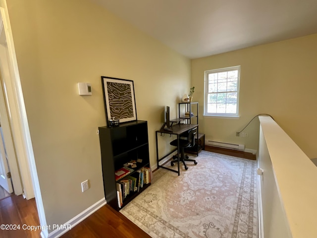 office with a baseboard heating unit, baseboards, and wood finished floors